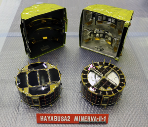 Fig. 3 - I due piccoli rover trasportati dalla microsonda Minerva-II1. Rover-1A e' quello a sinistra, Rover-1B quello a destra. In secondo piano, la capsula che li ospitava. Crediti: Jaxa.